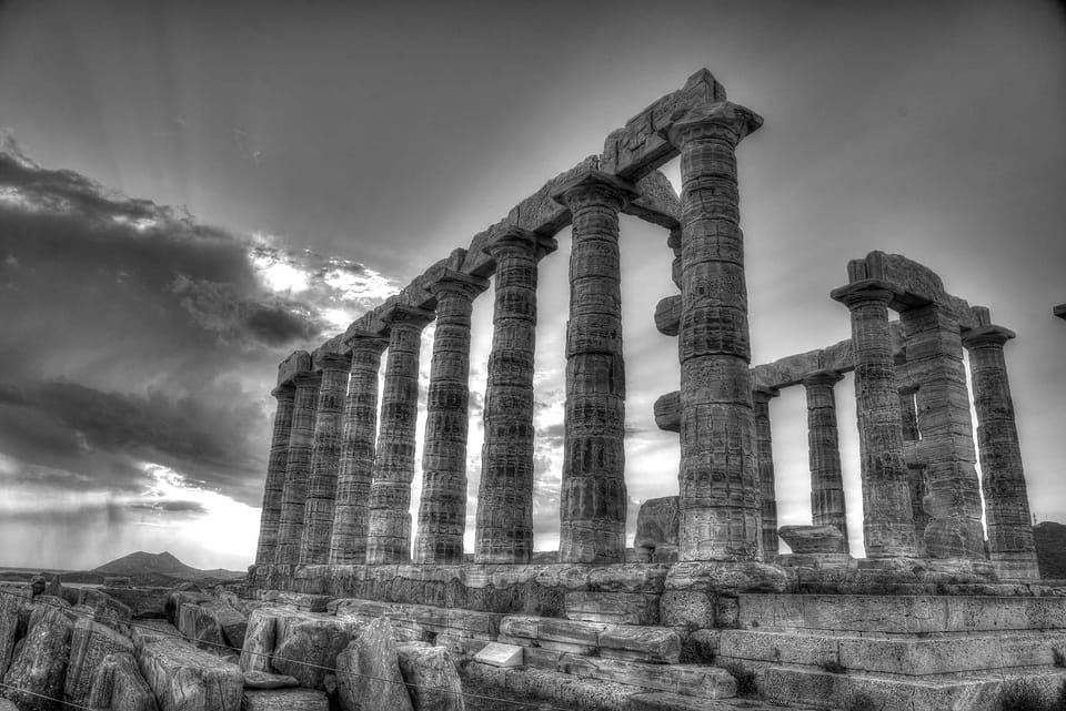 Templo de colunas dóricas em contraluz, sob um céu com nuvens